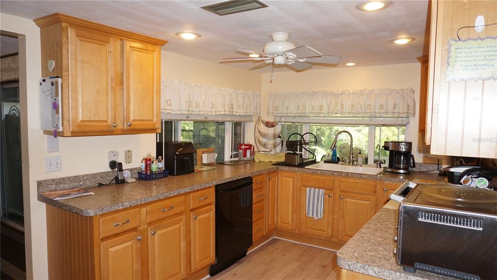 A kitchen features light wood cabinets, laminate countertops, a black dishwasher, and a ceiling fan — 12507 STONE HOUSE LOOP, HUDSON, FL