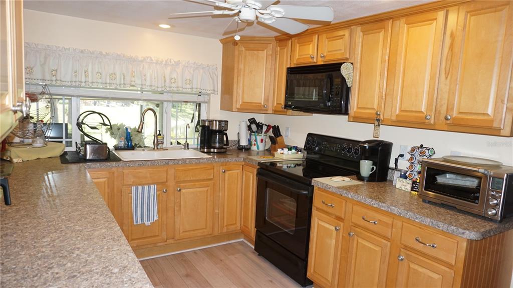A kitchen features light wood cabinets, black appliances, and a window above the sink — 12507 STONE HOUSE LOOP, HUDSON, FL