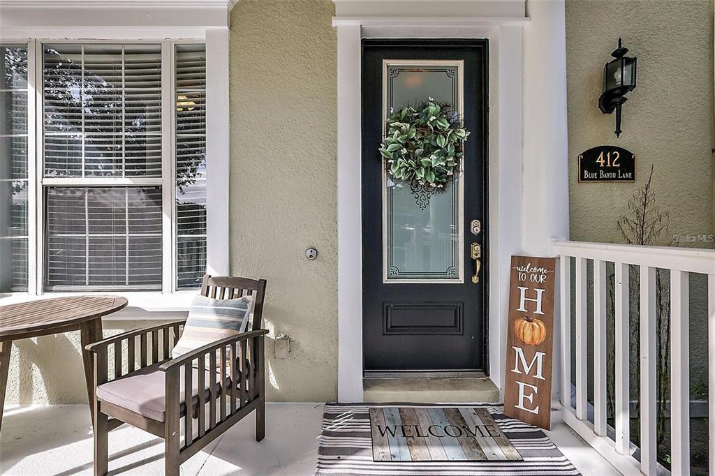 A front porch features a dark door with a wreath, a wooden chair, and decor — 412 BLUE BAYOU LANE, WINTER SPRINGS, FL
