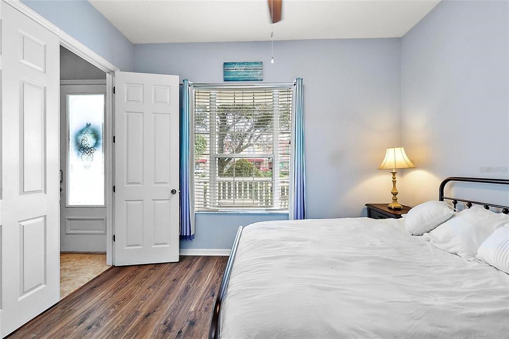 A bedroom features light blue walls, wood-look flooring, a white bed, and a window with blinds — 412 BLUE BAYOU LANE, WINTER SPRINGS, FL