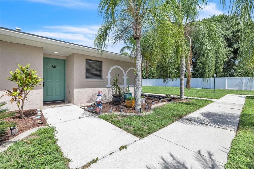 A tan exterior wall features a teal front door labeled A3 and palm trees — 24540 HARBORVIEW ROAD UNIT A3, PUNTA GORDA, FL