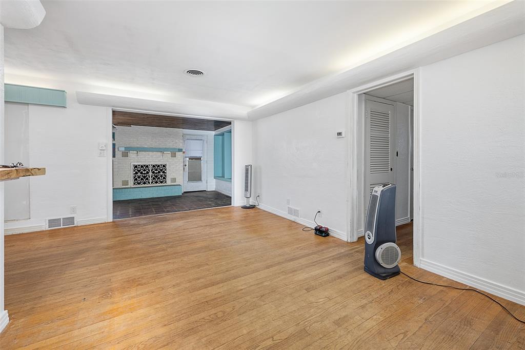 An interior room with hardwood floors, white walls, a ceiling fan, and a doorway leading outside — 1649 CORDOVA AVENUE, HOLLY HILL, FL