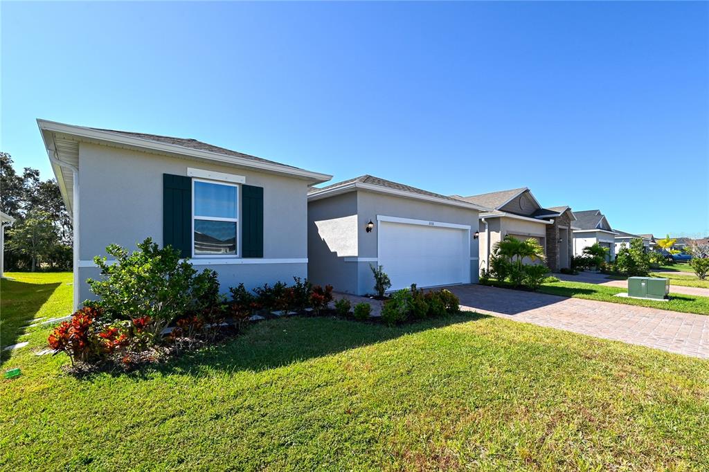 A single-story house with a gray exterior, white garage door, and a brick paver driveway — 3551 74TH AVENUE CIRCLE E, SARASOTA, FL