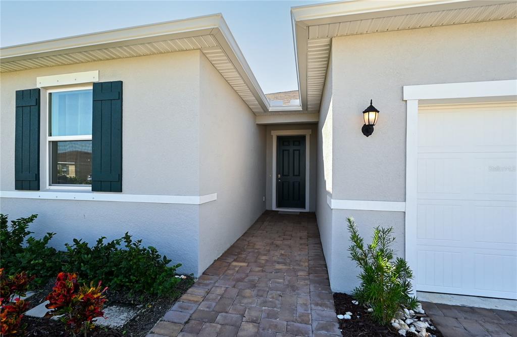 The exterior view shows a paved walkway leading to a dark front door between two walls — 3551 74TH AVENUE CIRCLE E, SARASOTA, FL