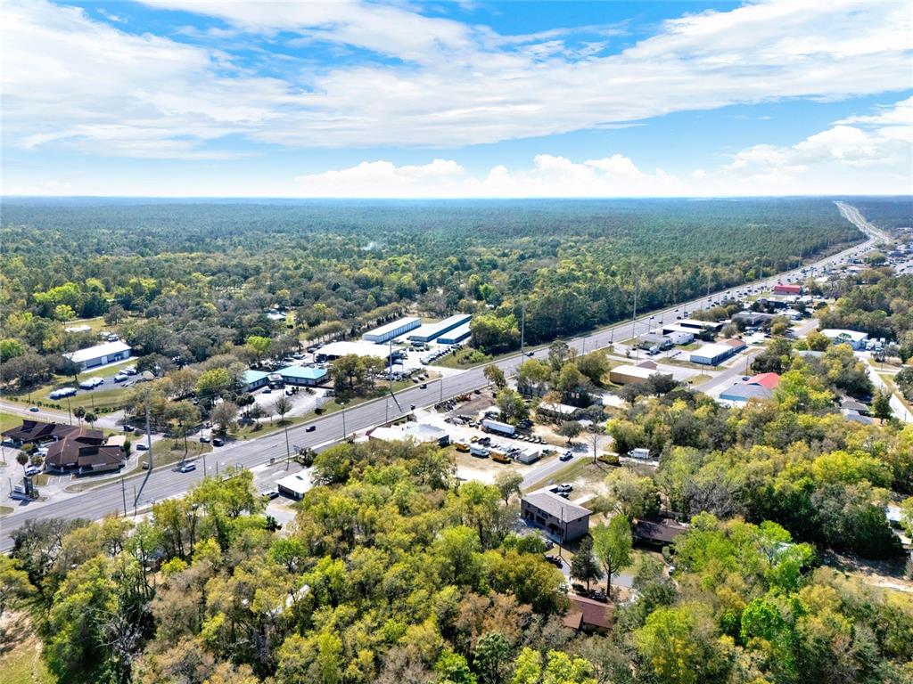 An aerial view shows a highway running through a wooded area with commercial buildings — 709 S SMITH AVENUE, INVERNESS, FL