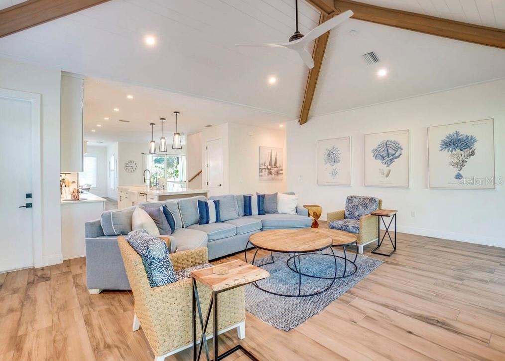 A bright living room features a large sectional sofa, wood-look flooring, and vaulted ceilings — 9403 GULF DR, ANNA MARIA, FL