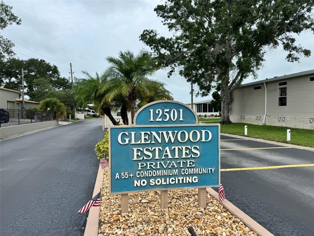 A sign for a 55+ condominium community stands in a landscaped area near a road — 12501 ULMERTON ROAD UNIT 193, LARGO, FL