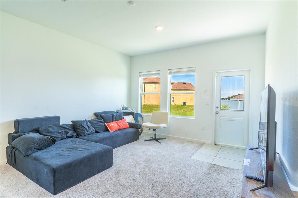 A living room features a dark sectional sofa, a white chair, and a glass door — 436 HENNEPIN LOOP, LAKE WALES, FL