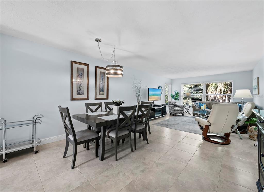 A dining area with a dark wood table and chairs opens into a living room — 3320 GULF OF MEXICO DRIVE UNIT 206C, LONGBOAT KEY, FL