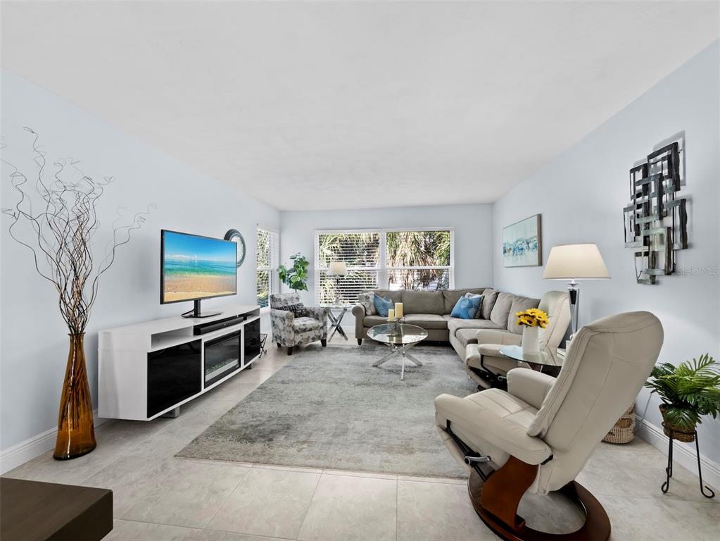 A living room features a sectional sofa, a recliner, a television, and a gray rug — 3320 GULF OF MEXICO DRIVE UNIT 206C, LONGBOAT KEY, FL