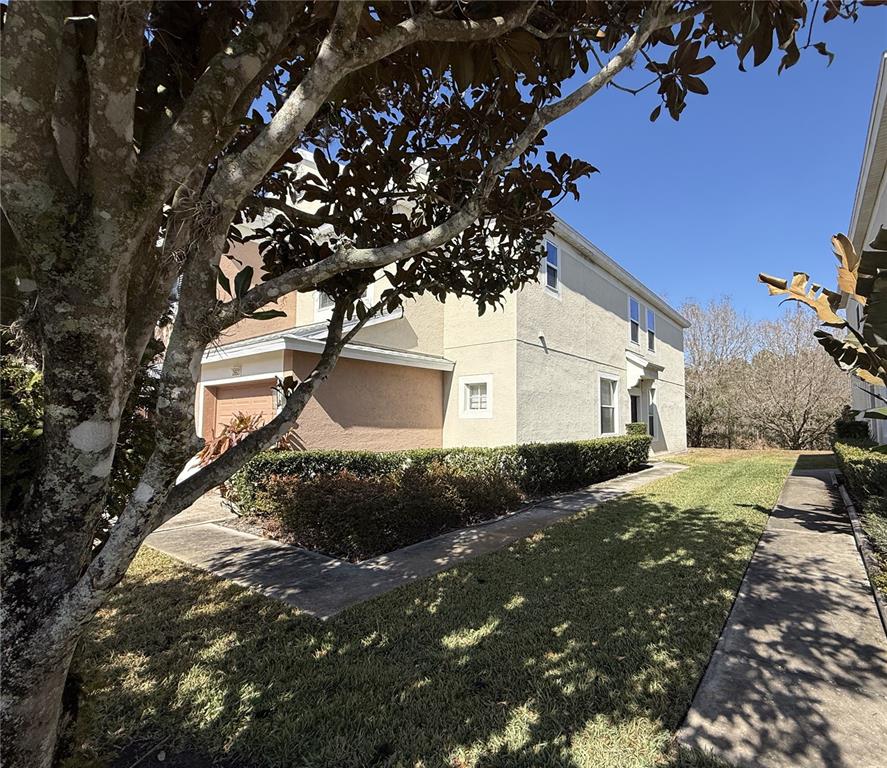 A two-story stucco house with a garage and a sidewalk surrounded by green landscaping — 26627 CASTLEVIEW WAY, WESLEY CHAPEL, FL