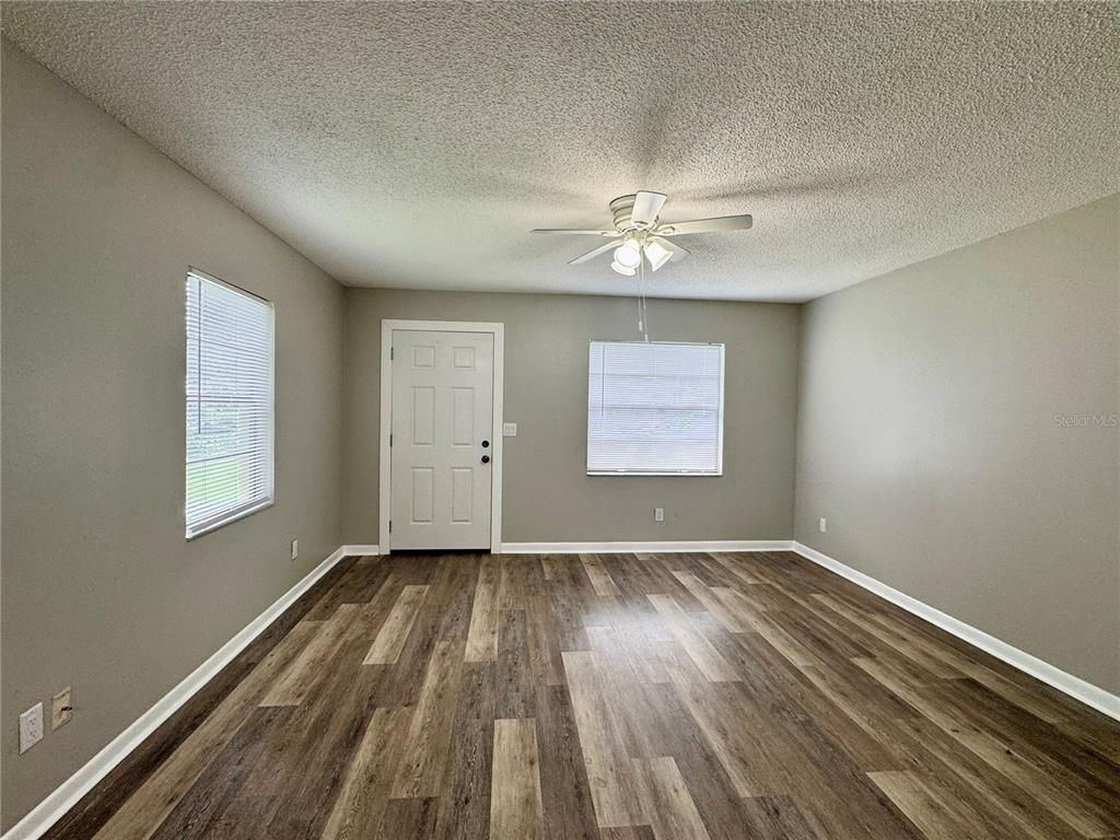 An open living area features wood-look flooring, a ceiling fan, and a kitchen pass-through window — 5619 PEACH AVENUE, SEFFNER, FL