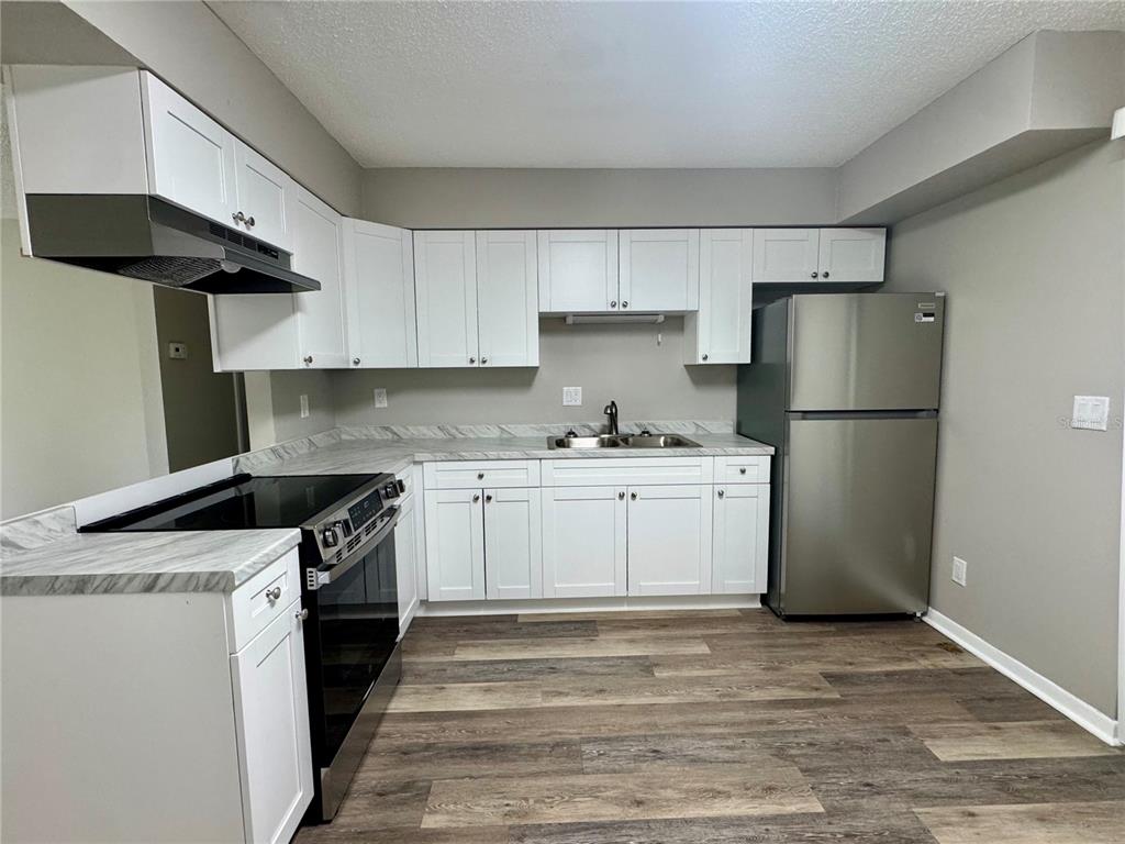 An open living area features wood-look flooring, a ceiling fan, and a kitchen breakfast bar — 5619 PEACH AVENUE, SEFFNER, FL