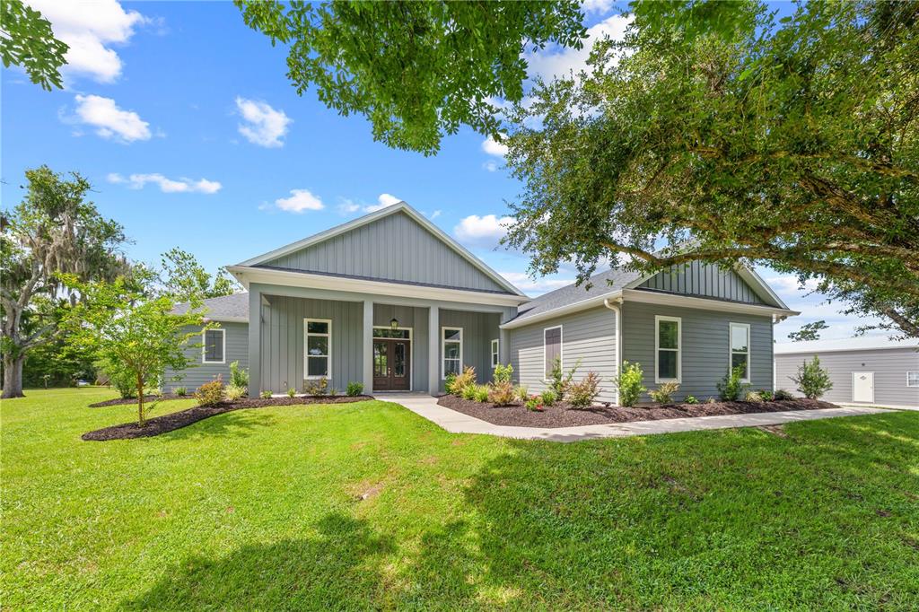 A gray single-story house with board-and-batten siding, a covered porch, and a large front lawn — 4024 SYLVESTER DRIVE, ST CLOUD, FL