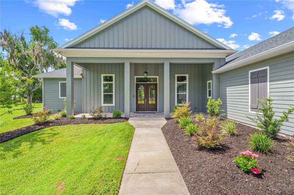 A gray house with vertical siding features a covered front porch and a concrete walkway — 4024 SYLVESTER DRIVE, ST CLOUD, FL