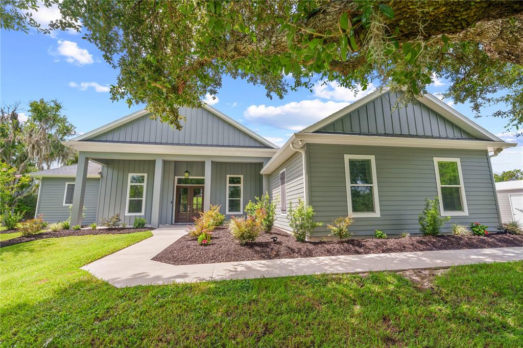 A single-story house with gray siding, a covered entryway, and a concrete walkway — 4024 SYLVESTER DRIVE, ST CLOUD, FL