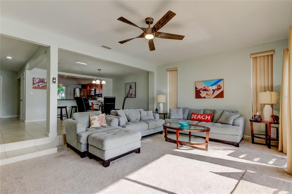 A living room features a sectional sofa, a glass coffee table, and a media console — 135 92ND AVENUE UNIT 5, TREASURE ISLAND, FL