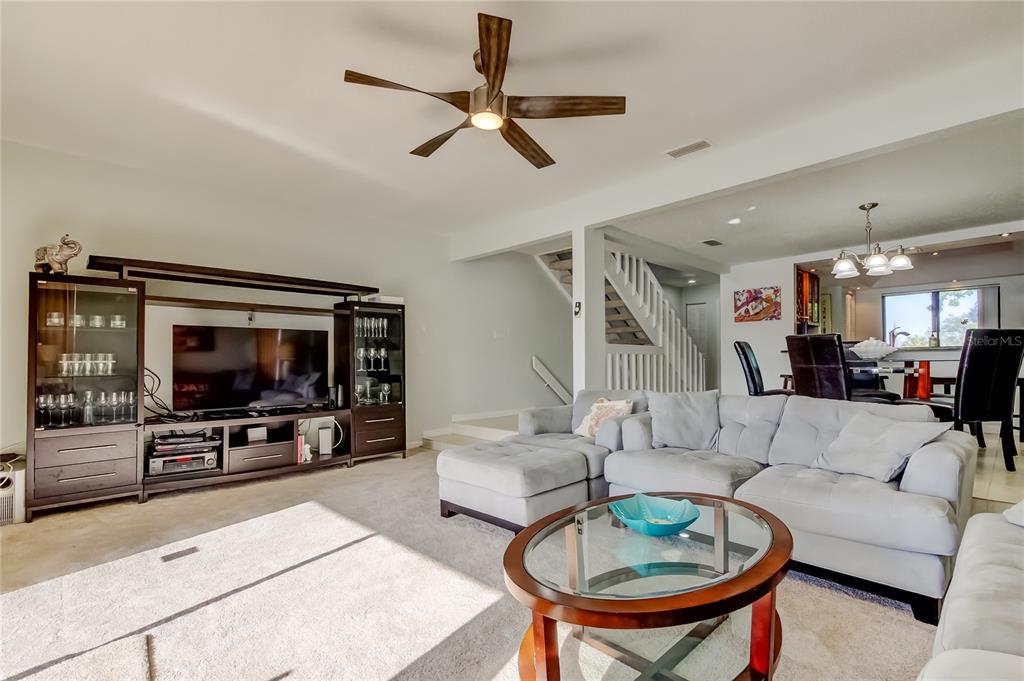 A living room features a gray sectional sofa, a ceiling fan, and a sliding glass door — 135 92ND AVENUE UNIT 5, TREASURE ISLAND, FL