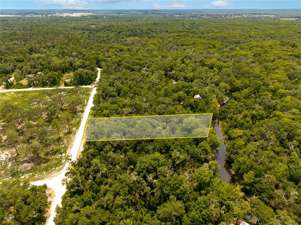 An aerial view shows a rectangular plot of land highlighted in yellow near a creek — 7353 RIVERVIEW DRIVE, WEBSTER, FL