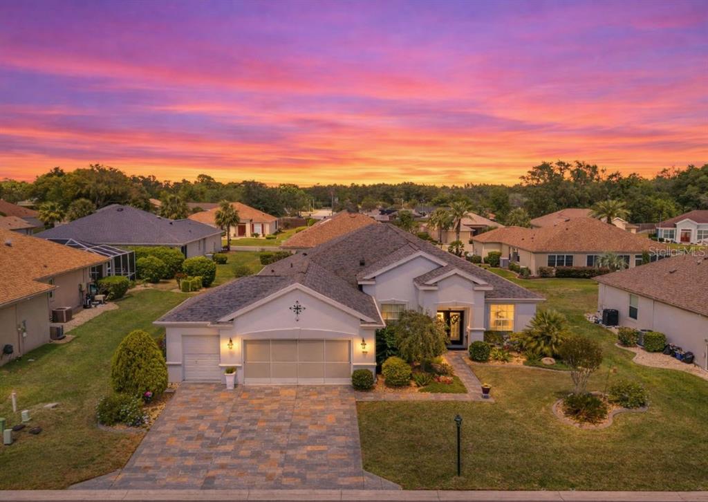 An aerial view of a single-story suburban house with a paved driveway at sunset — 9290 SE 120TH LOOP, SUMMERFIELD, FL