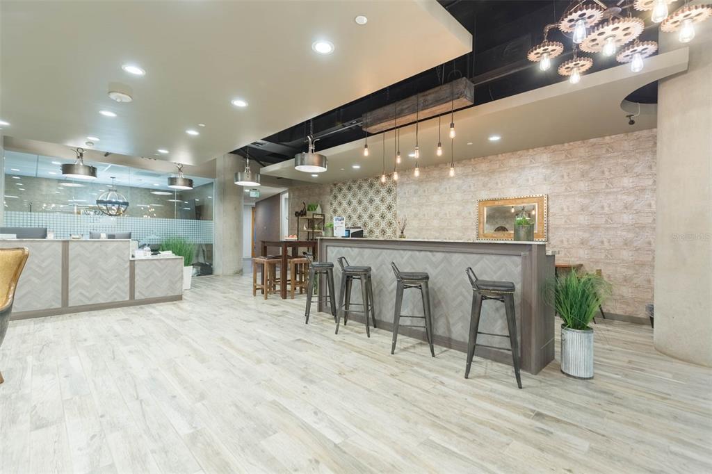 A modern office lobby features a long reception desk, bar-style seating, and industrial-style lighting fixtures — 400 N ASHLEY DRIVE UNIT 1927, TAMPA, FL