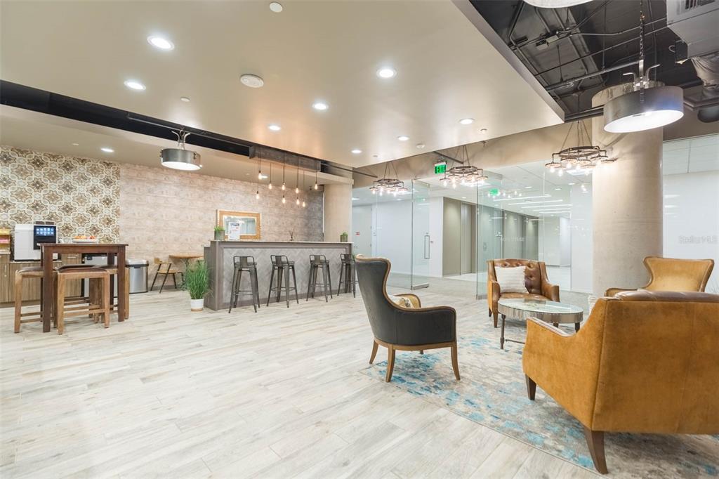 A modern office lobby features a reception desk, lounge seating, and wood-look tile flooring — 400 N ASHLEY DRIVE UNIT 1927, TAMPA, FL
