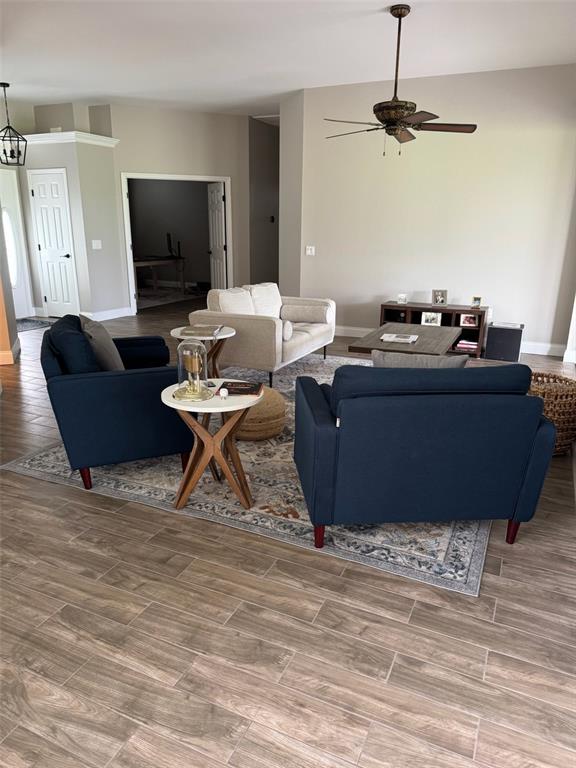 A living room features wood-look tile flooring, a ceiling fan, and a seating area with blue armchairs — 6623 BENDELOW DRIVE, LAKELAND, FL