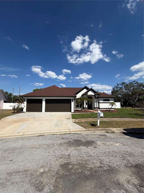 A single-story house with a two-car garage, white stucco walls, and a brown roof — 8137 GOLDEN BEAR LOOP, PORT RICHEY, FL