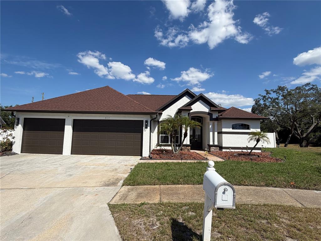 A single-story house with a brown roof, white stucco exterior, and a two-car garage — 8137 GOLDEN BEAR LOOP, PORT RICHEY, FL