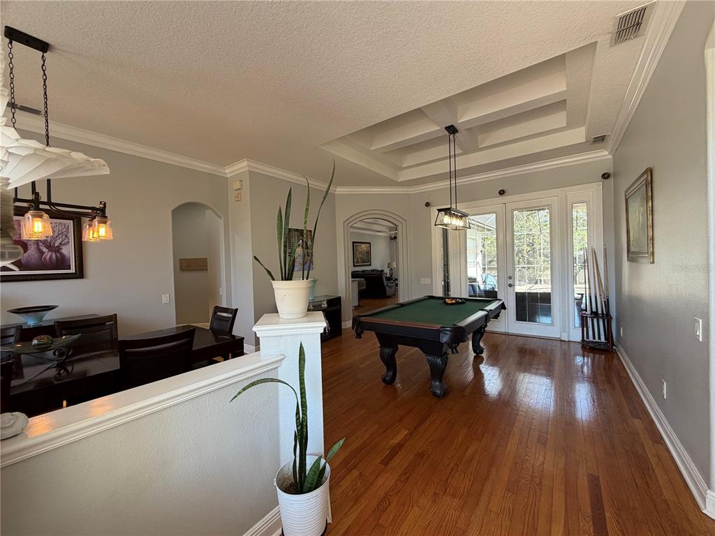A dining area and game room feature a pool table, hardwood floors, and coffered ceilings — 8137 GOLDEN BEAR LOOP, PORT RICHEY, FL
