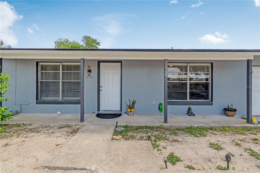 The exterior of a gray, single-story house features a front porch and a white door — 2633 BEAL STREET, DELTONA, FL