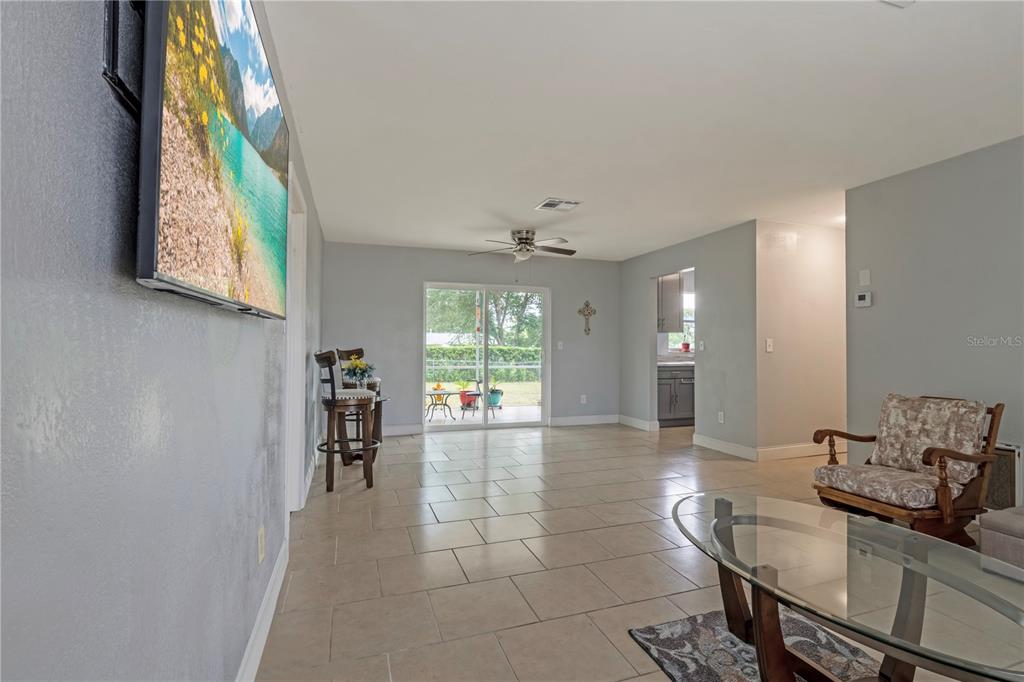 A living room with tile flooring, a mounted television, and a sliding glass door — 2633 BEAL STREET, DELTONA, FL