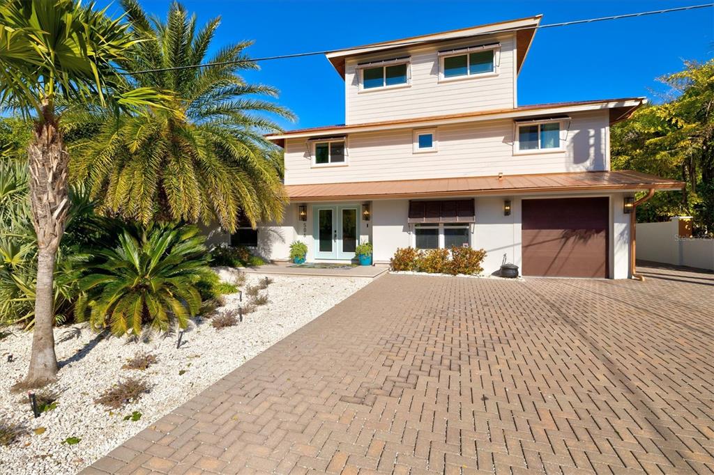 A three-story house with light siding, a paved driveway, and a palm tree in front — 506 58TH STREET, HOLMES BEACH, FL