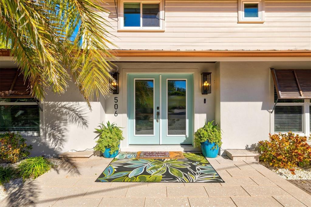 The front exterior of a house features a light blue double door and a patterned rug — 506 58TH STREET, HOLMES BEACH, FL