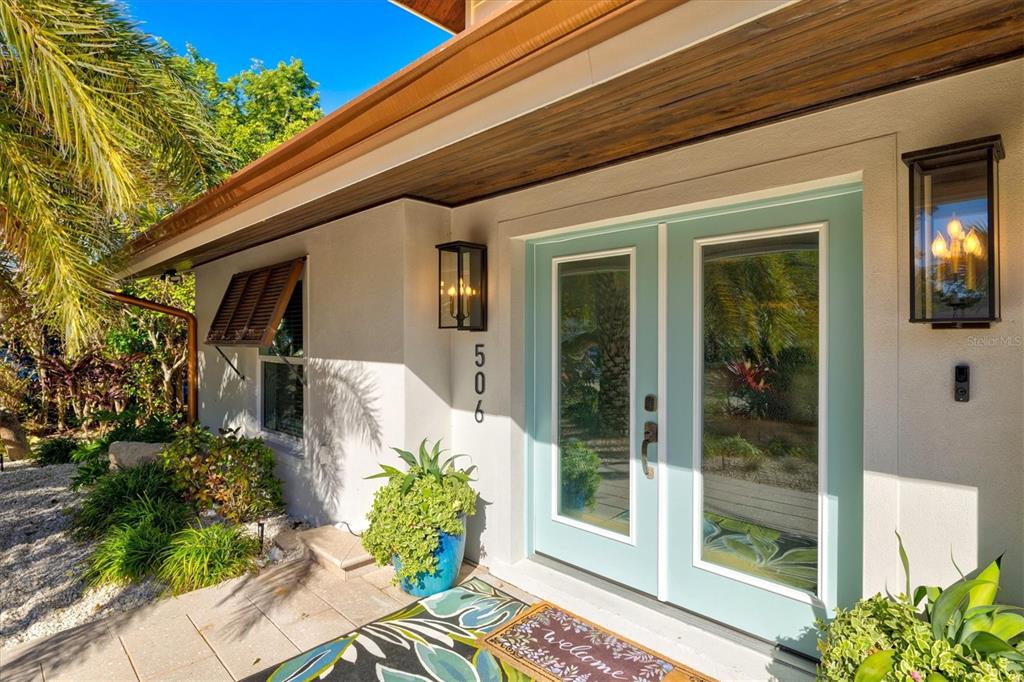 The exterior entrance features a light blue double door, house number 506, and wall lanterns — 506 58TH STREET, HOLMES BEACH, FL