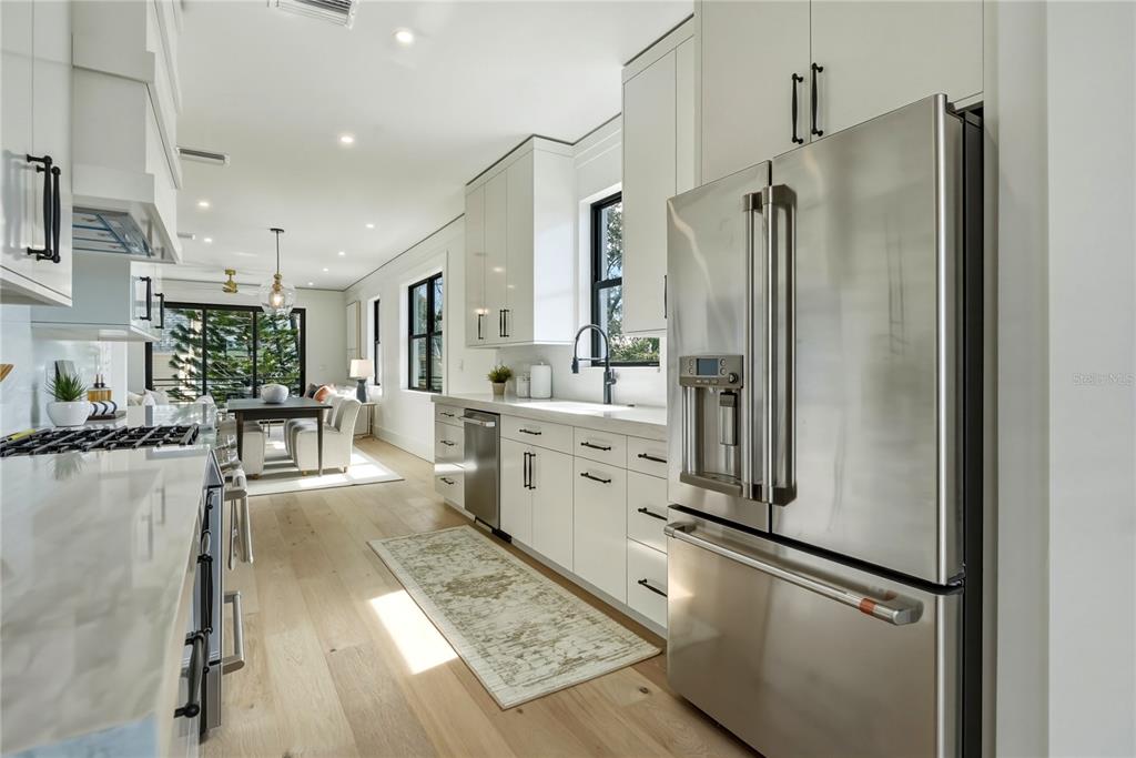 A modern kitchen features white cabinetry, stainless steel appliances, and light wood flooring — 205 BATES AVENUE UNIT A, INDIAN ROCKS BEACH, FL