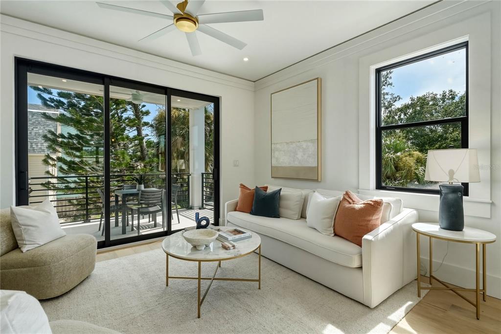 A bright living room features a white sofa, marble coffee table, and sliding glass doors — 205 BATES AVENUE UNIT A, INDIAN ROCKS BEACH, FL