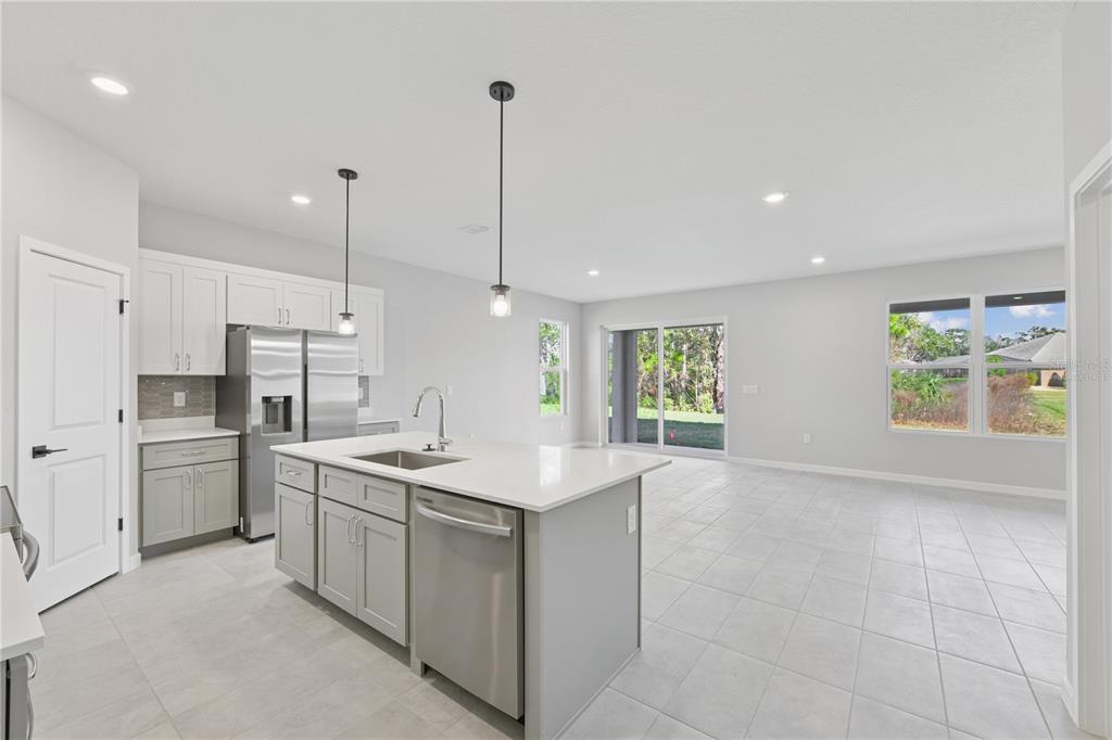 A kitchen with a center island, stainless steel appliances, and white cabinets opens to a living area — 17843 SW 68TH PLACE, DUNNELLON, FL
