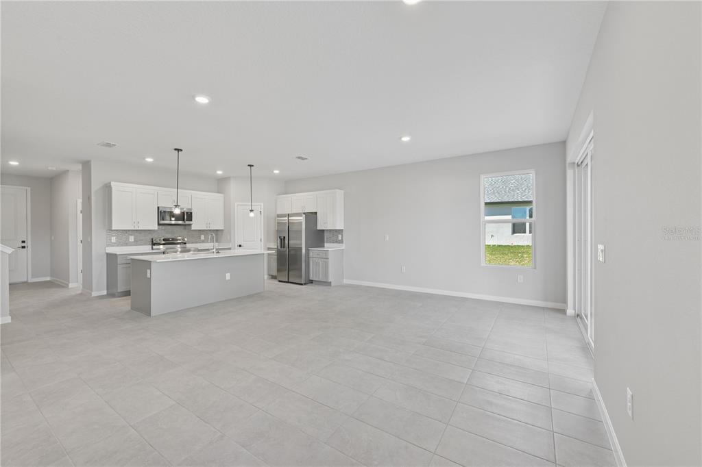 A bright, open-concept kitchen and living area with light gray tile flooring and white cabinetry — 17843 SW 68TH PLACE, DUNNELLON, FL