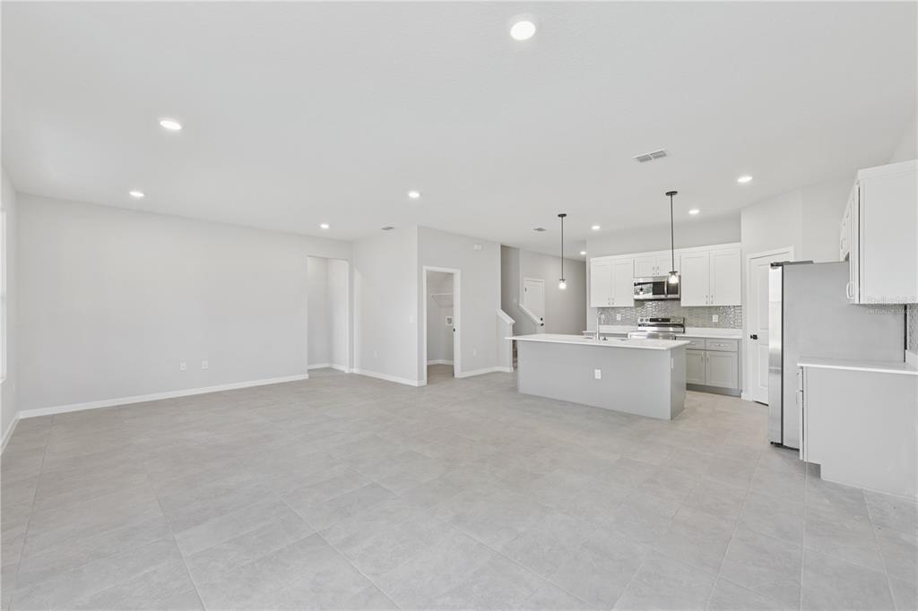 An open-concept kitchen and living area features gray tile flooring, white cabinetry, and a peninsula — 17843 SW 68TH PLACE, DUNNELLON, FL