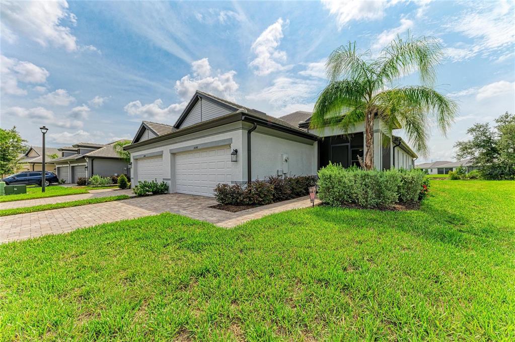 A single-story house with a two-car garage, a palm tree, and a paved driveway — 18048 CHERISHED LOOP, LAKEWOOD RANCH, FL