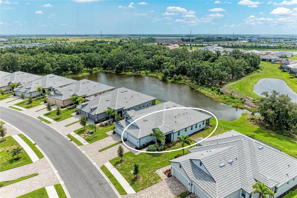 An aerial view shows a suburban house with a gray tiled roof near a pond — 18048 CHERISHED LOOP, LAKEWOOD RANCH, FL