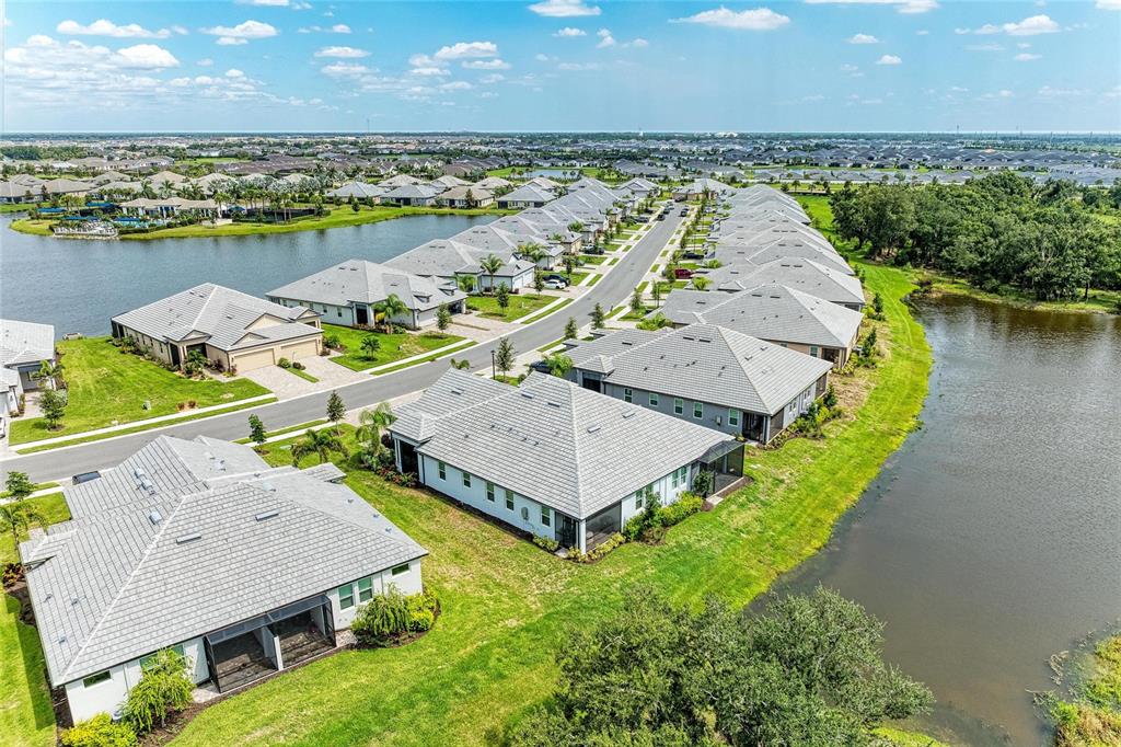An aerial view shows suburban houses with gray roofs situated along a street and ponds — 18048 CHERISHED LOOP, LAKEWOOD RANCH, FL