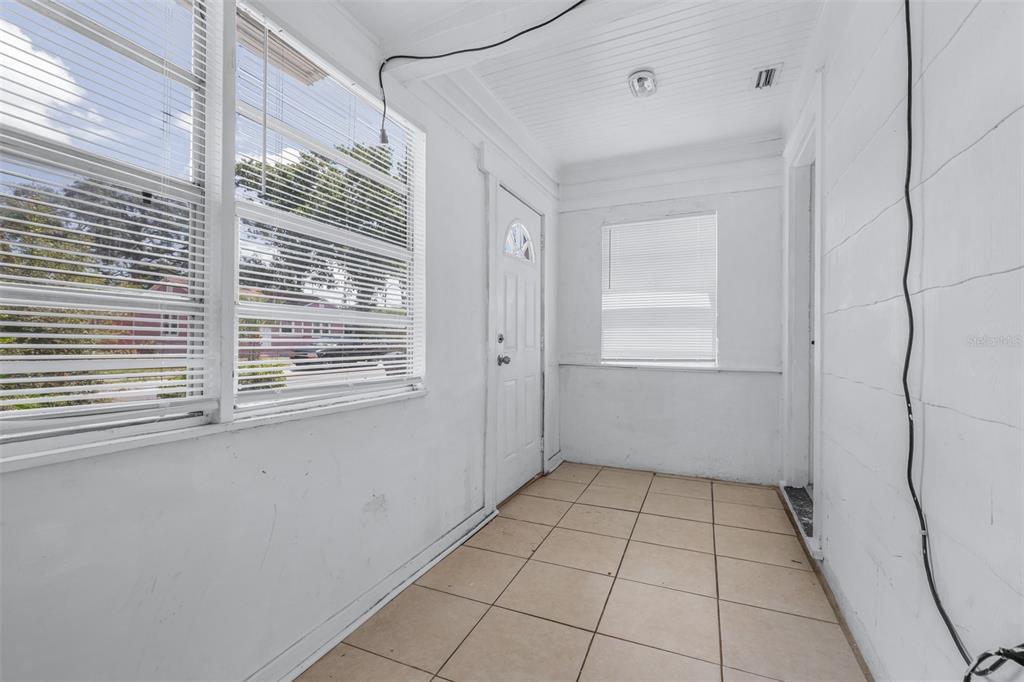 A sunroom with white walls, tiled flooring, and multiple windows with blinds — 1311 PRESCOTT STREET S, ST PETERSBURG, FL