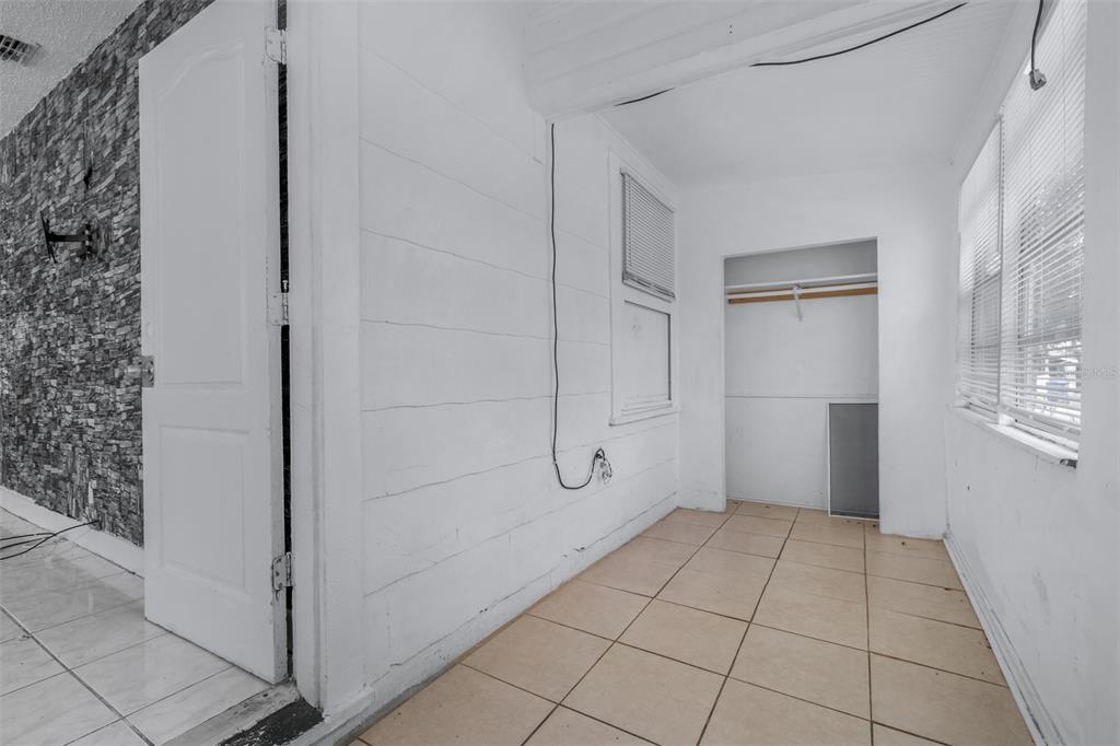 A small, white-walled room with tiled flooring, a closet, and a stone-accented wall — 1311 PRESCOTT STREET S, ST PETERSBURG, FL