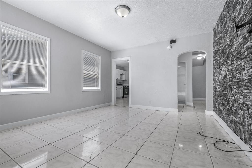 A room with white tiled floors, light gray walls, two windows, and a stone-textured wall — 1311 PRESCOTT STREET S, ST PETERSBURG, FL