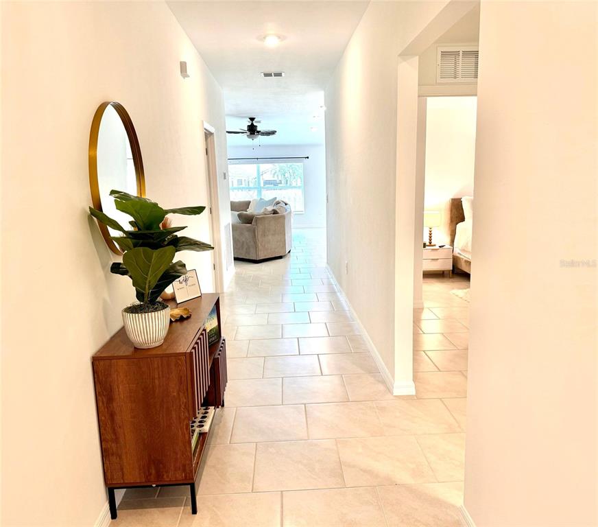 A hallway with tile flooring leads from a foyer toward a living room — 1207 SHEEHAN BOULEVARD, PORT CHARLOTTE, FL