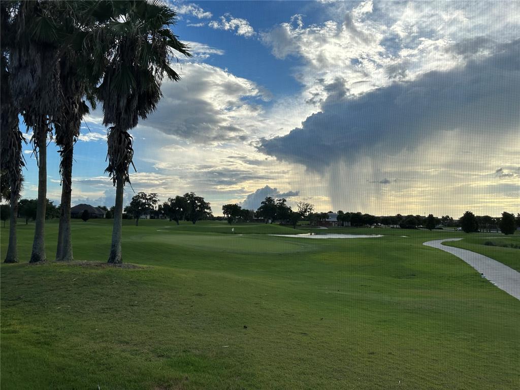 A view of a golf course green and pond from behind a screen enclosure — 2841 APACHE COURT, THE VILLAGES, FL