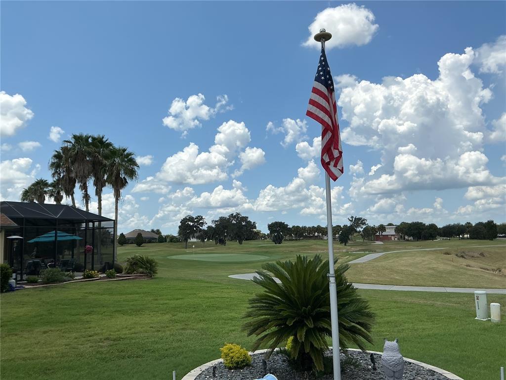 A gray house exterior features a white-framed screen door, arched window, and stone paver walkway — 2841 APACHE COURT, THE VILLAGES, FL