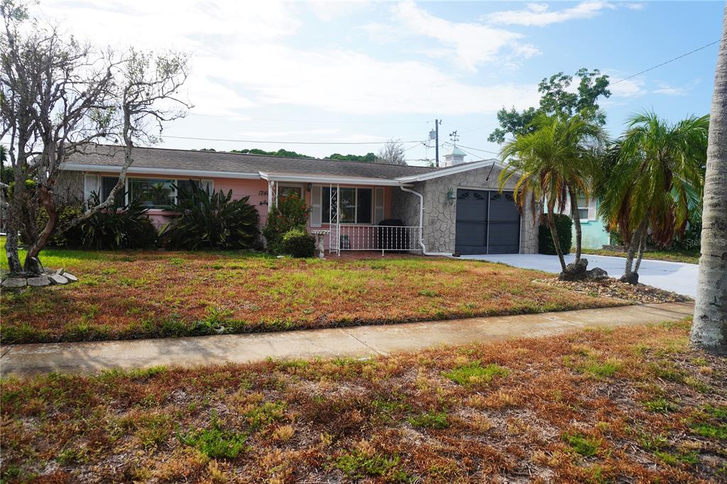 A single-story house with a pink exterior, stone facade, and a front porch — 1248 ERMINE DRIVE, HOLIDAY, FL